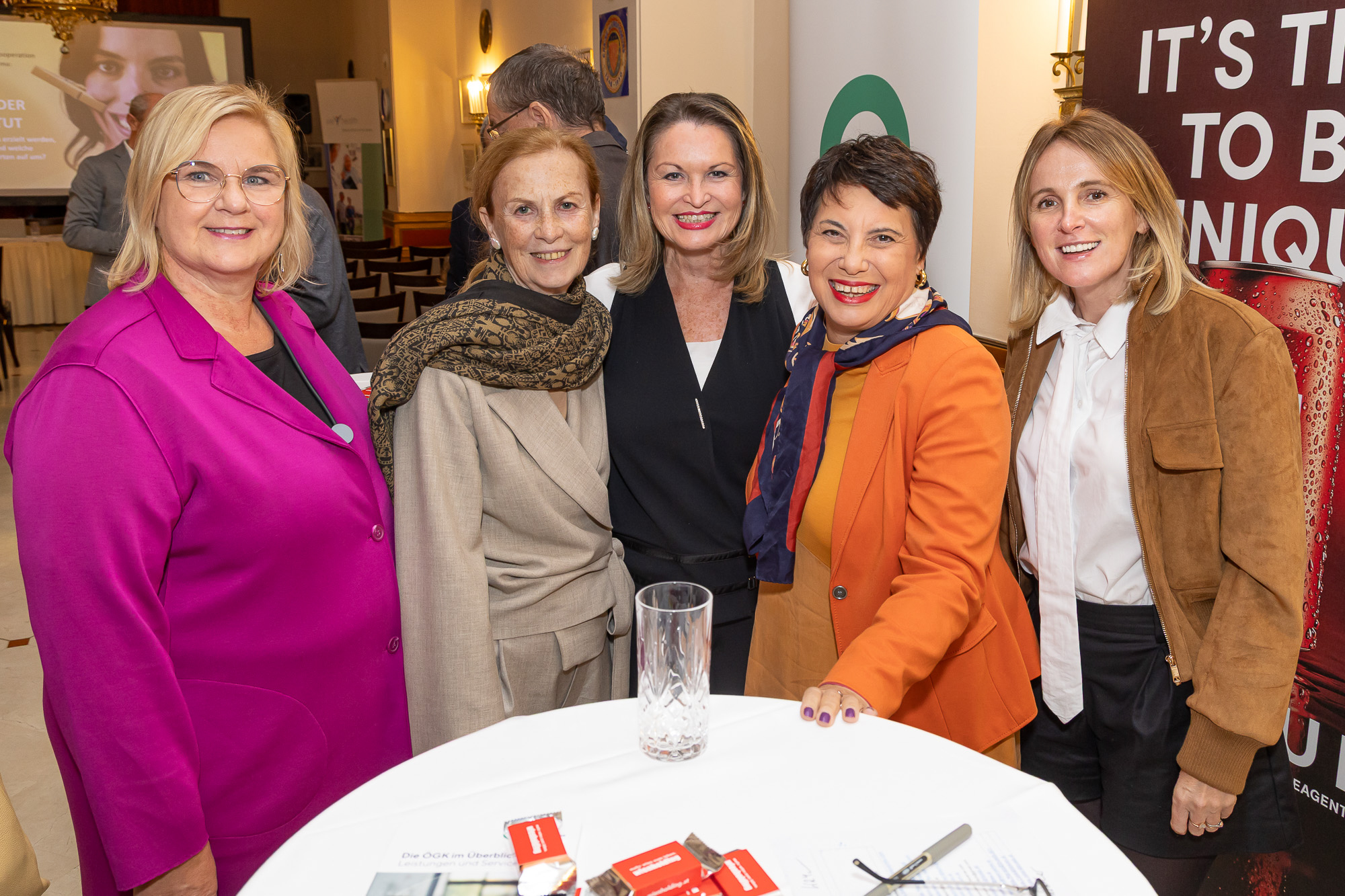 Fünf Frauen stehen lächelnd an einem Stehtisch bei der Jubiläumsveranstaltung.