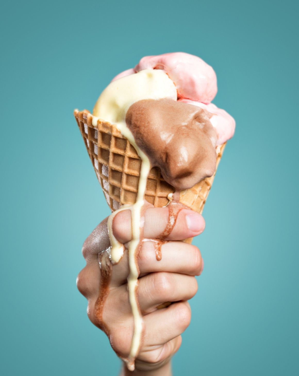hand holding a melting ice cream cone