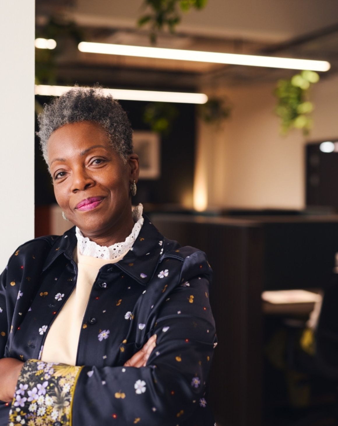 smiling black woman with arms crossed in an office setting