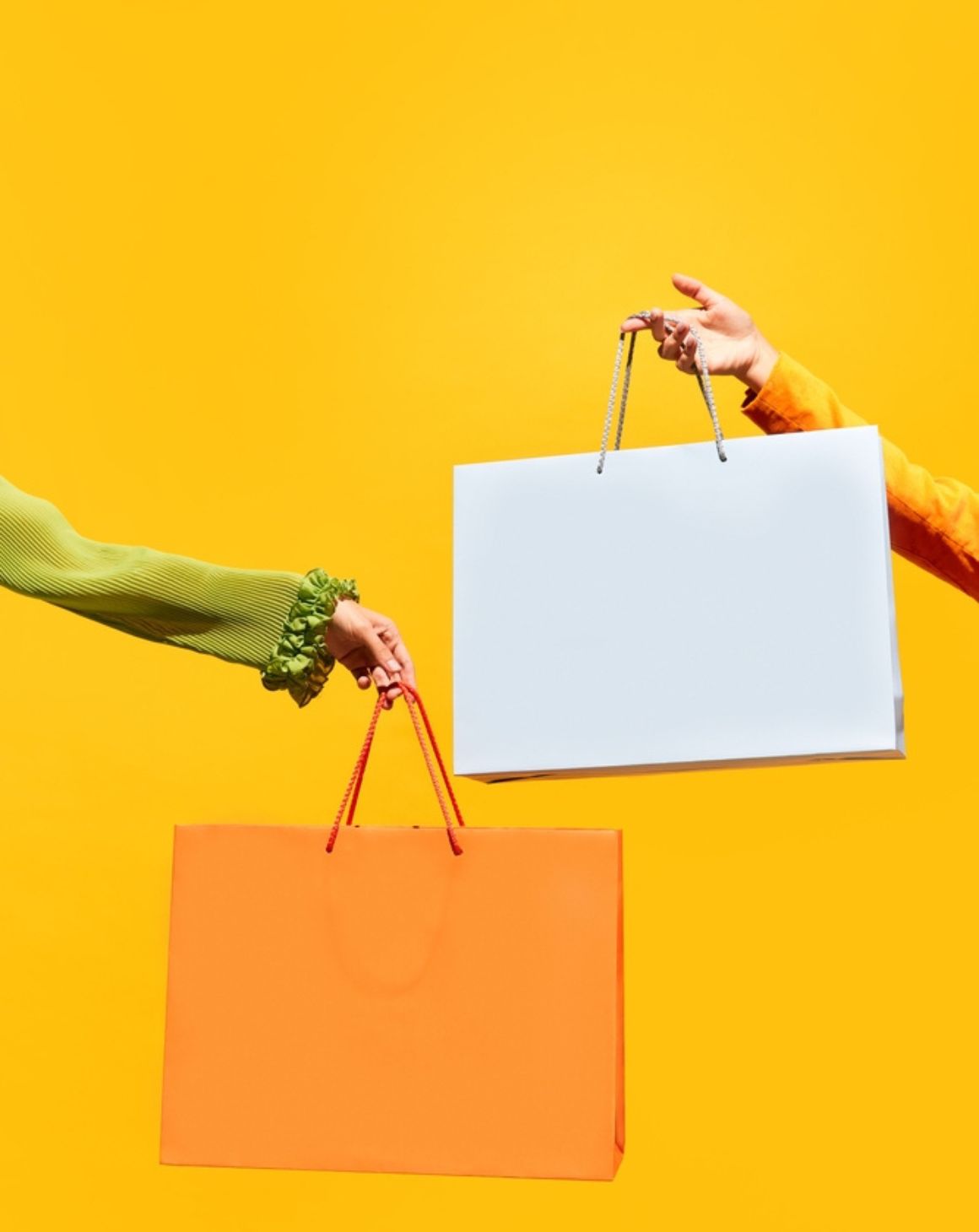 two women with shopping bags stand on a bright yellow background
