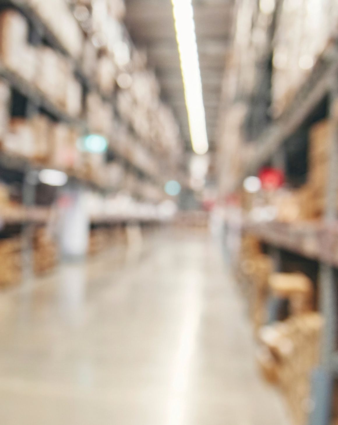 blurred view of a warehouse aisle filled with stacked boxes and shelves