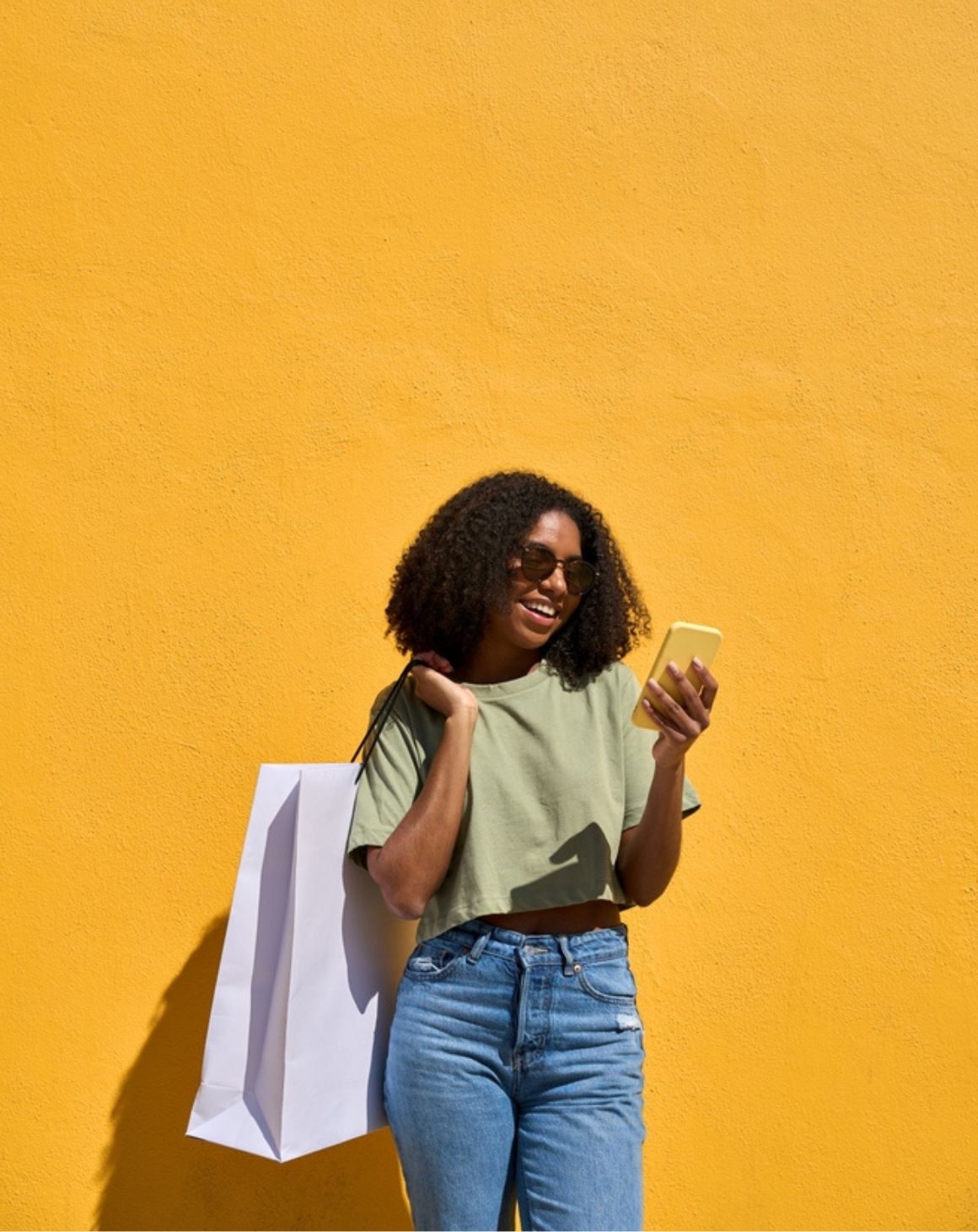 a woman holding a shopping bag while looking at her phone