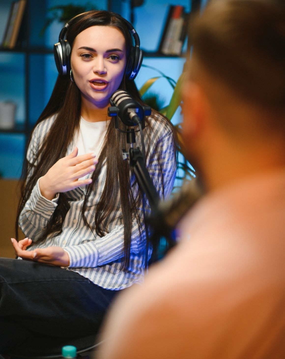 woman wearing headphones in front of a microphone in a podcast setting