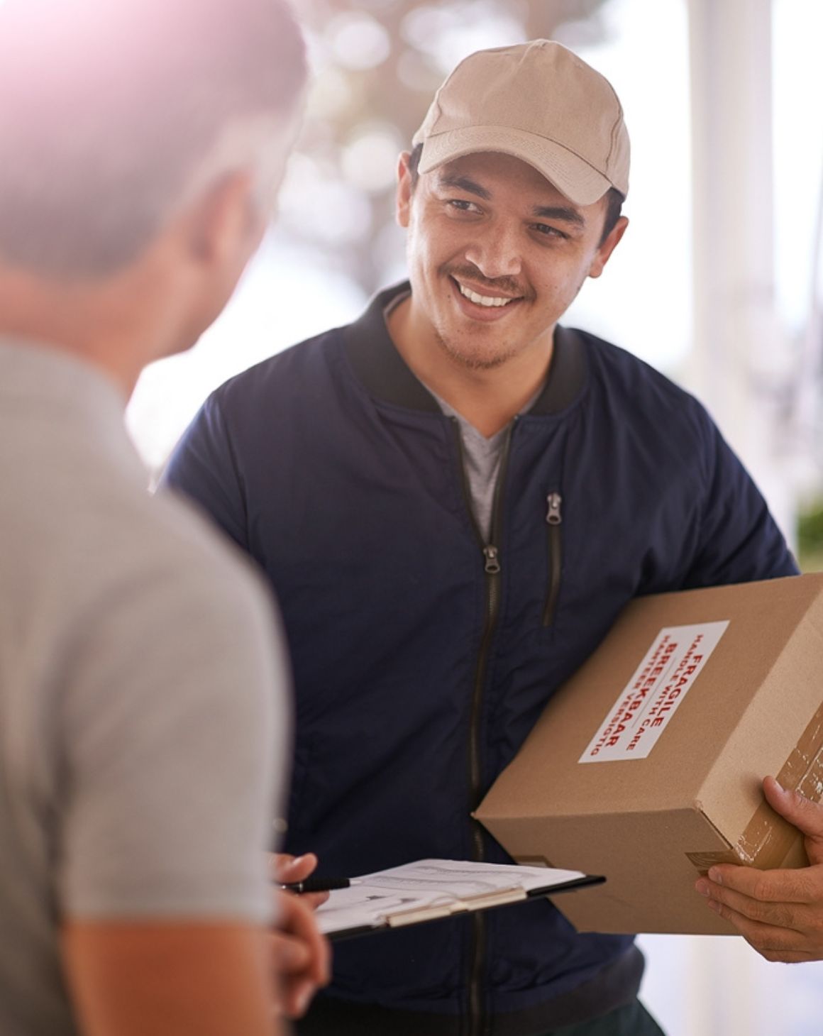 delivery man holds a box while another man signs for the delivery