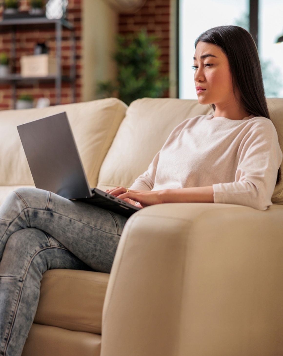 a woman sitting on a couch focused on her laptop