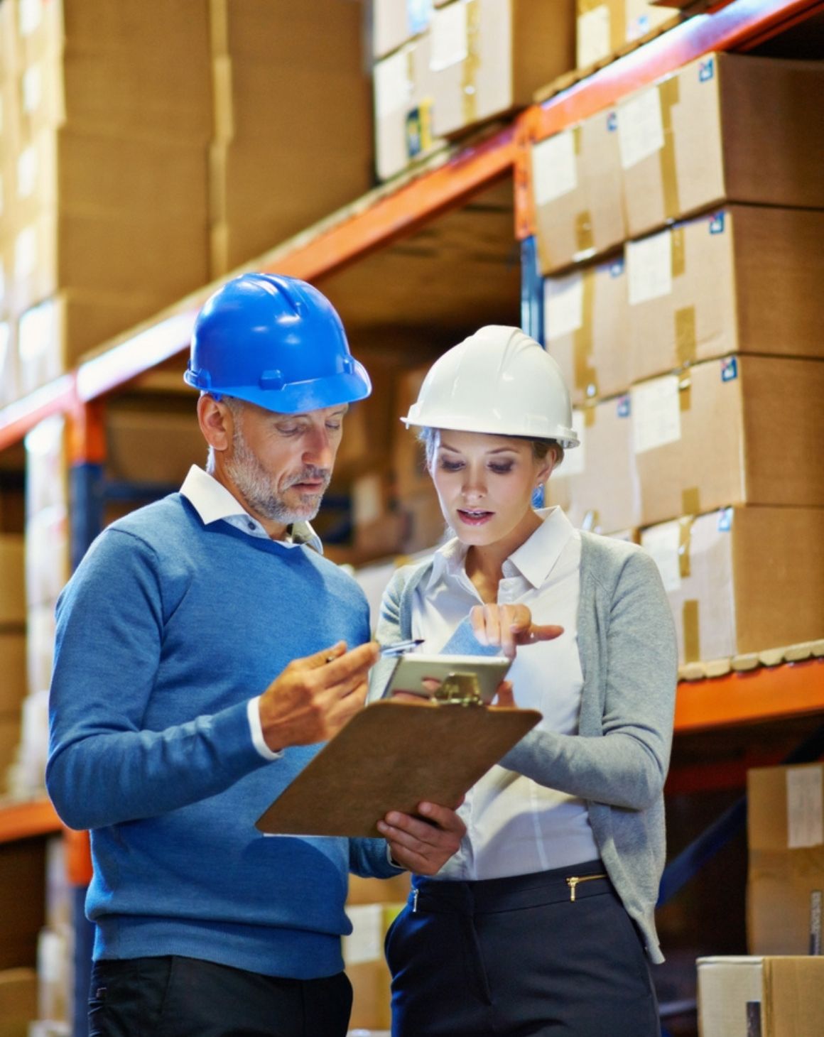 a man and woman in a warehouse reviewing a clipboard