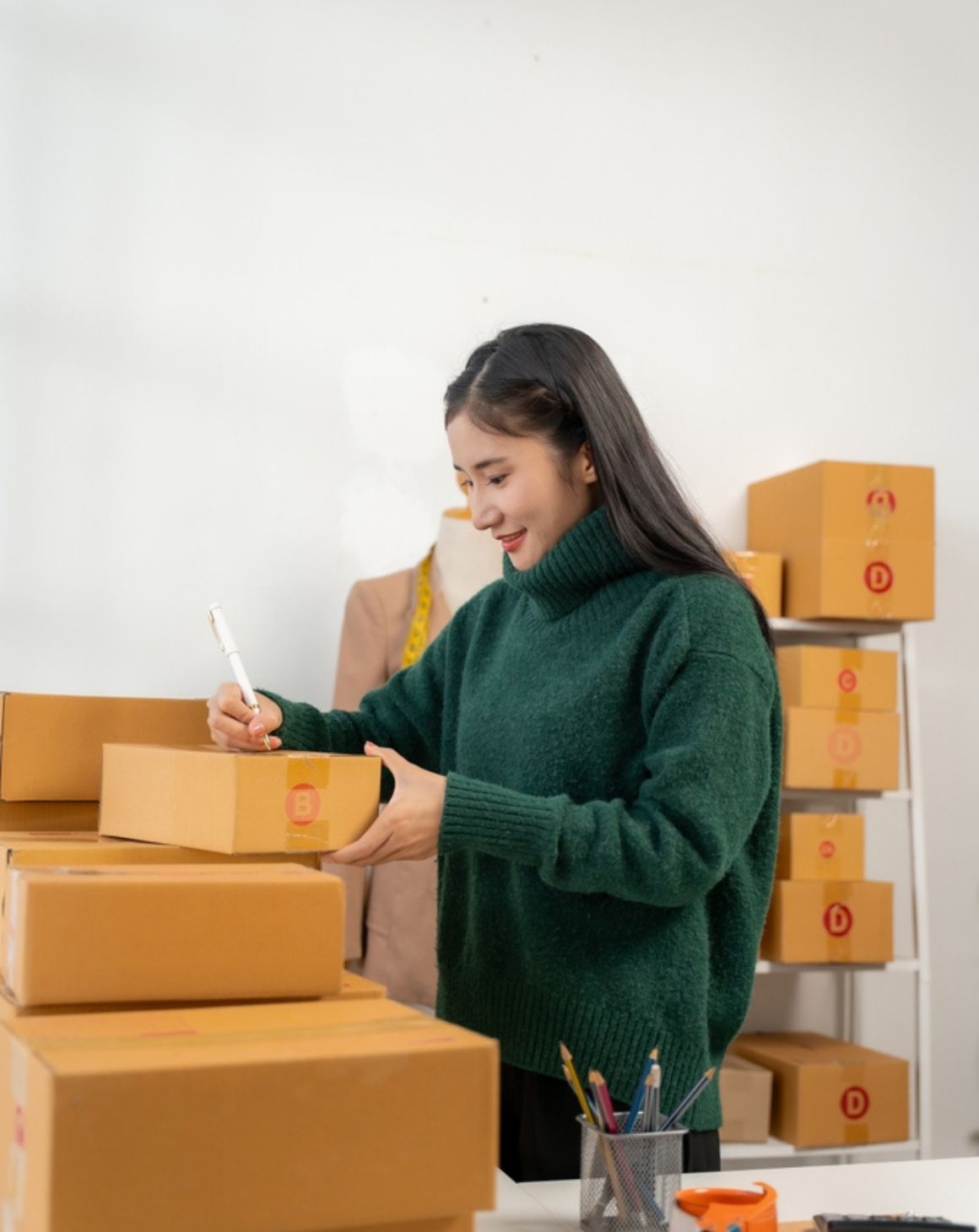 woman writing on a box in a room surrounded by shipments
