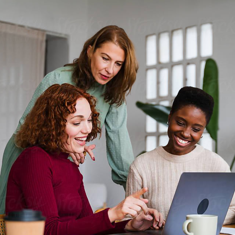 a group of adults smiling around a laptop