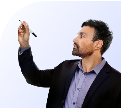 Man in a dark blazer and purple shirt holding a black and white marker as if writing on a board.