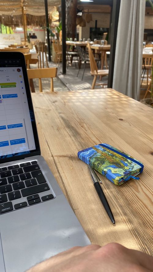 Siting on the laptop having a notepad near me on a beach bar