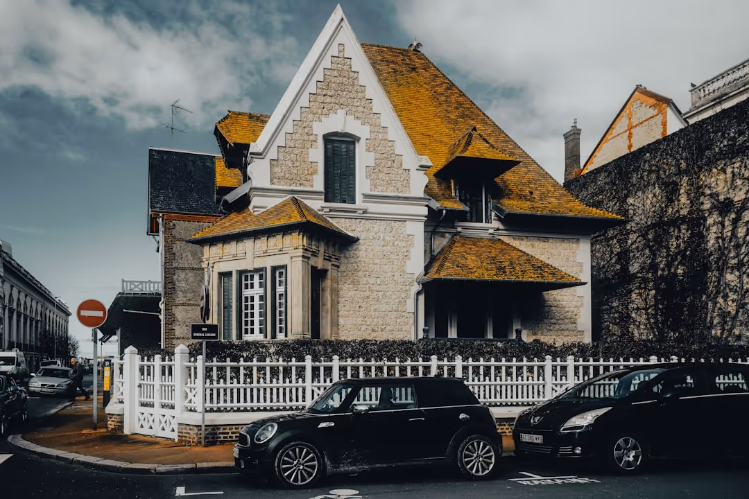 Stone house with yellow moss-covered roof and white picket fence