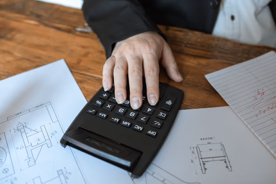 A calculator and blueprints on a desk - building contractor insurance A calculator and blueprints on a desk - building contractor insurance