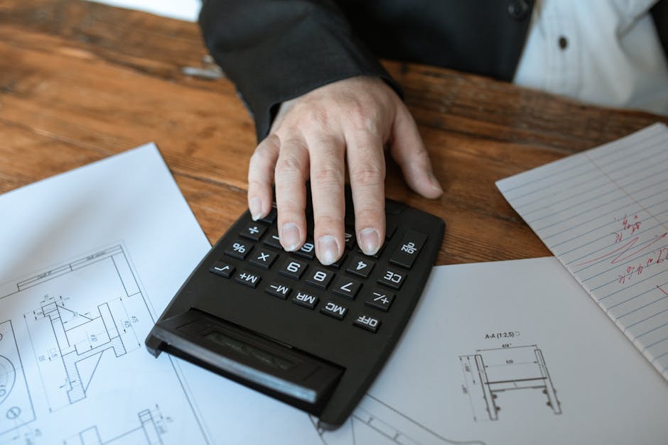 A calculator and blueprints on a desk - building contractor insurance