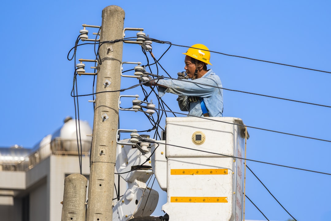 electrian working on top of electrical pole - electrical contractor insurance concept