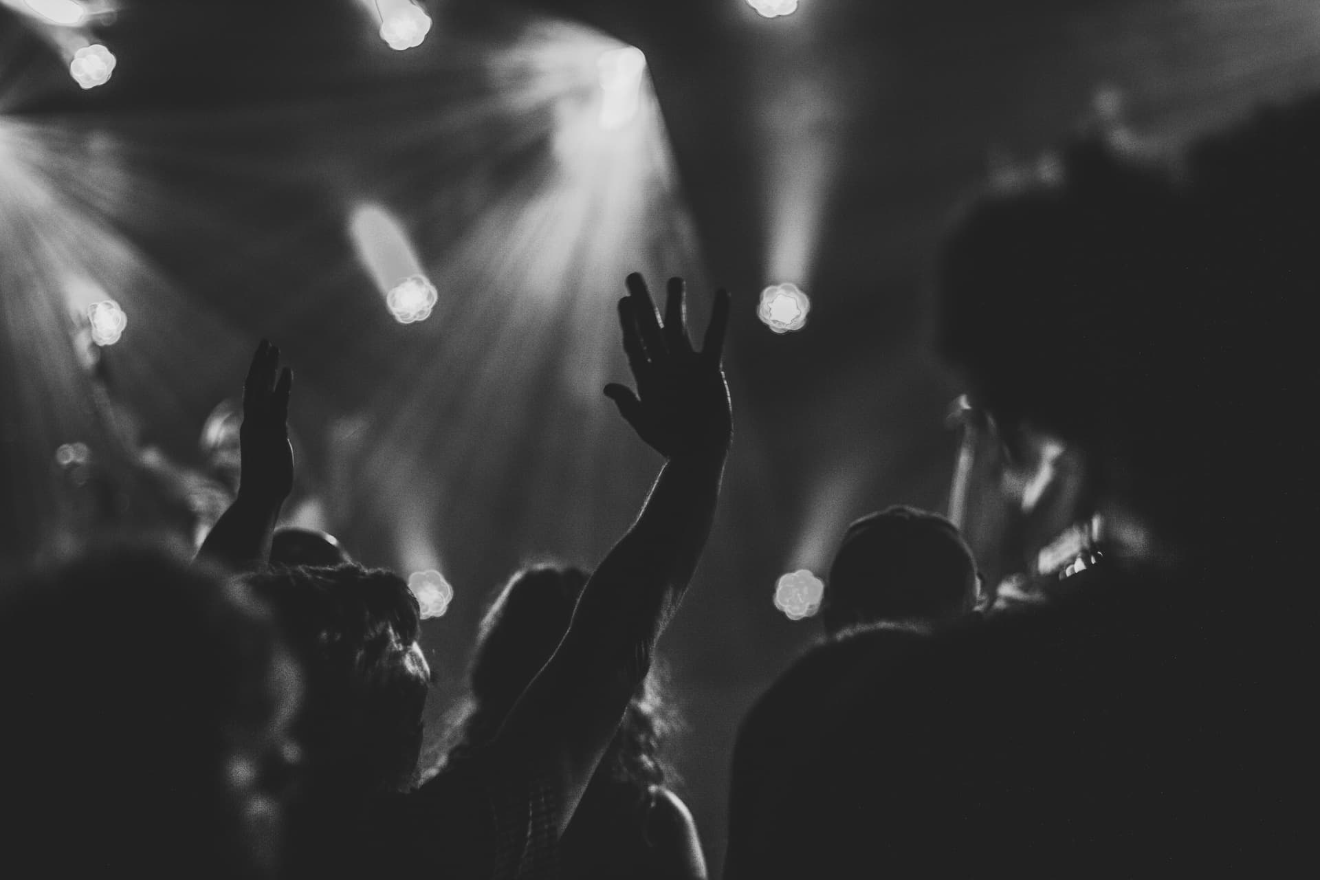 People worshipping with hands up in black and white filter