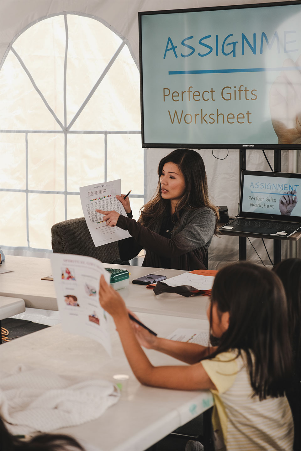 Woman holding up paper at school to toddler