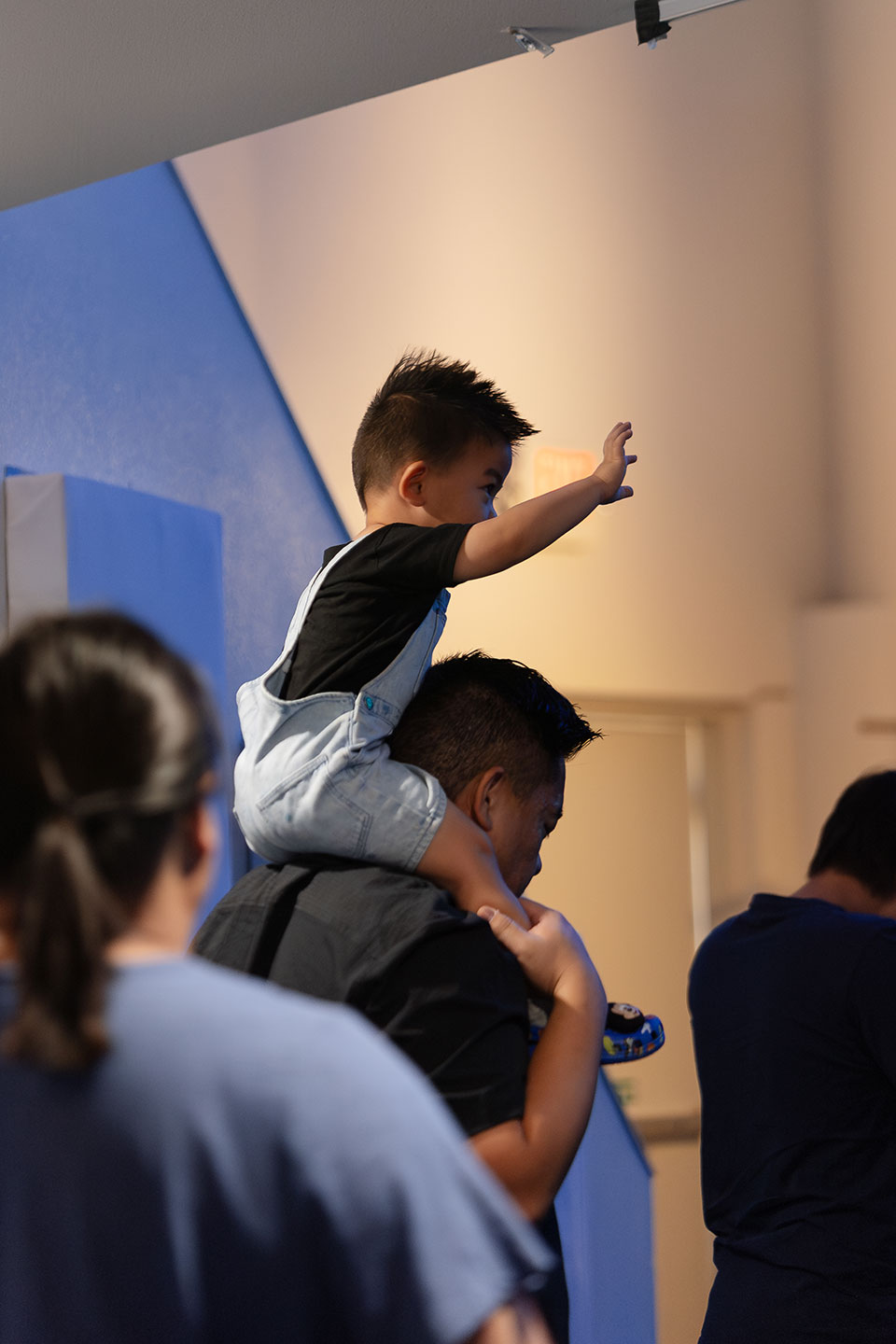 Kid on father's shoulders worshipping with hands up