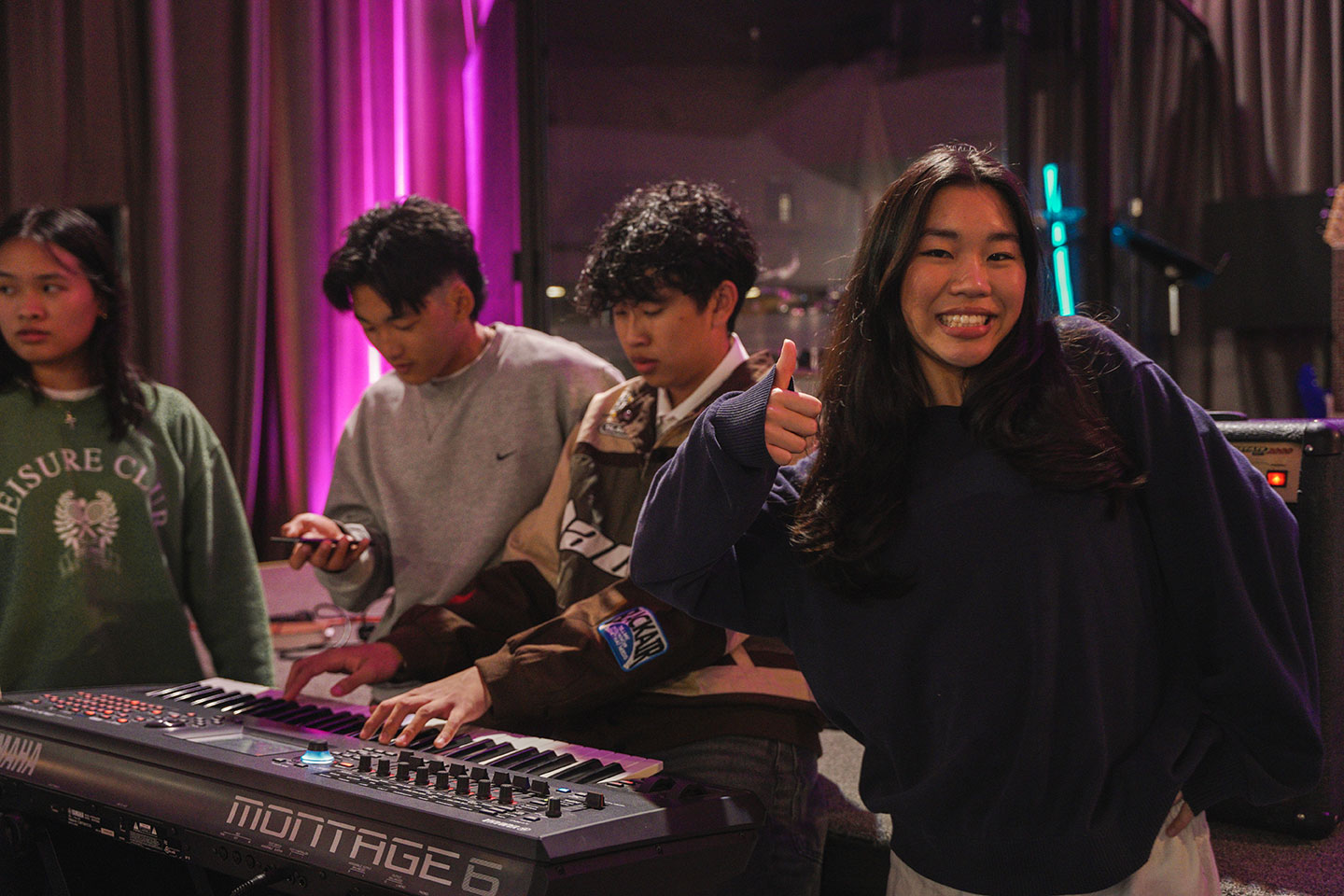 Four teenagers standing in front of piano