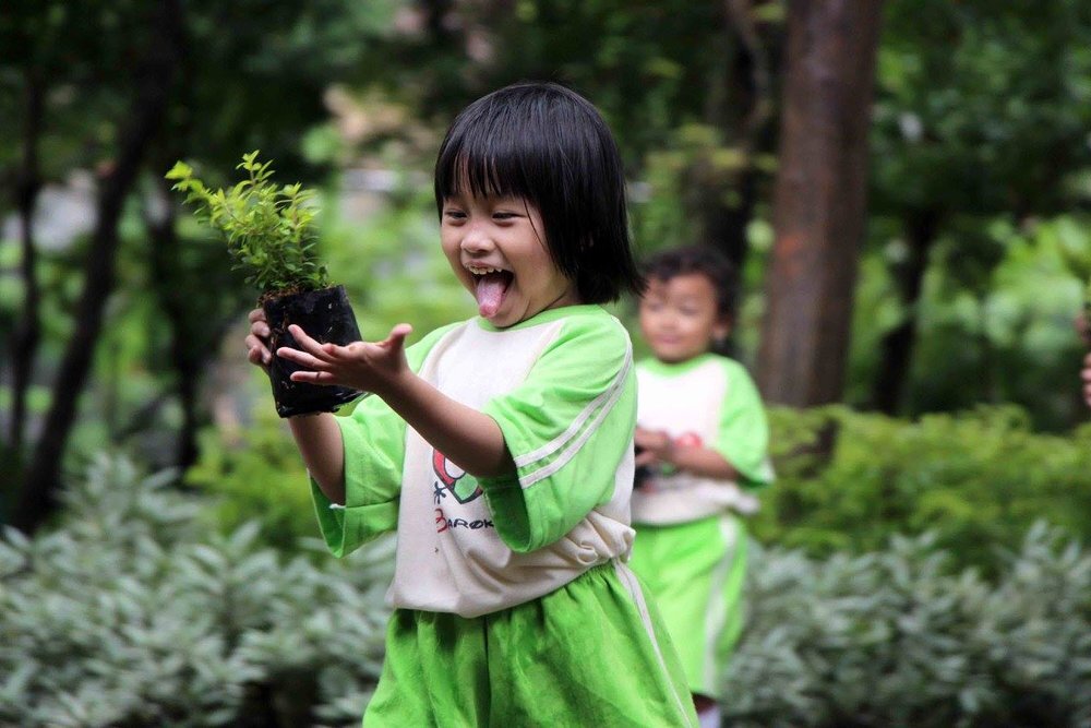 Excited toddler holding a plant up 