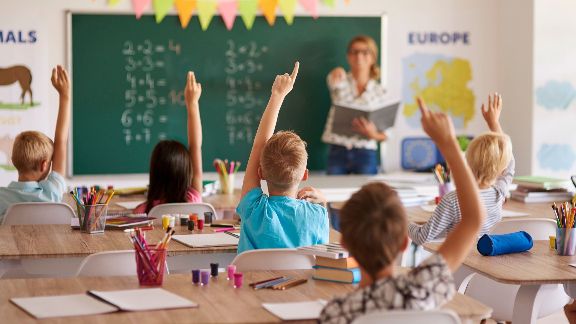 Children raising hands to answer question for teacher