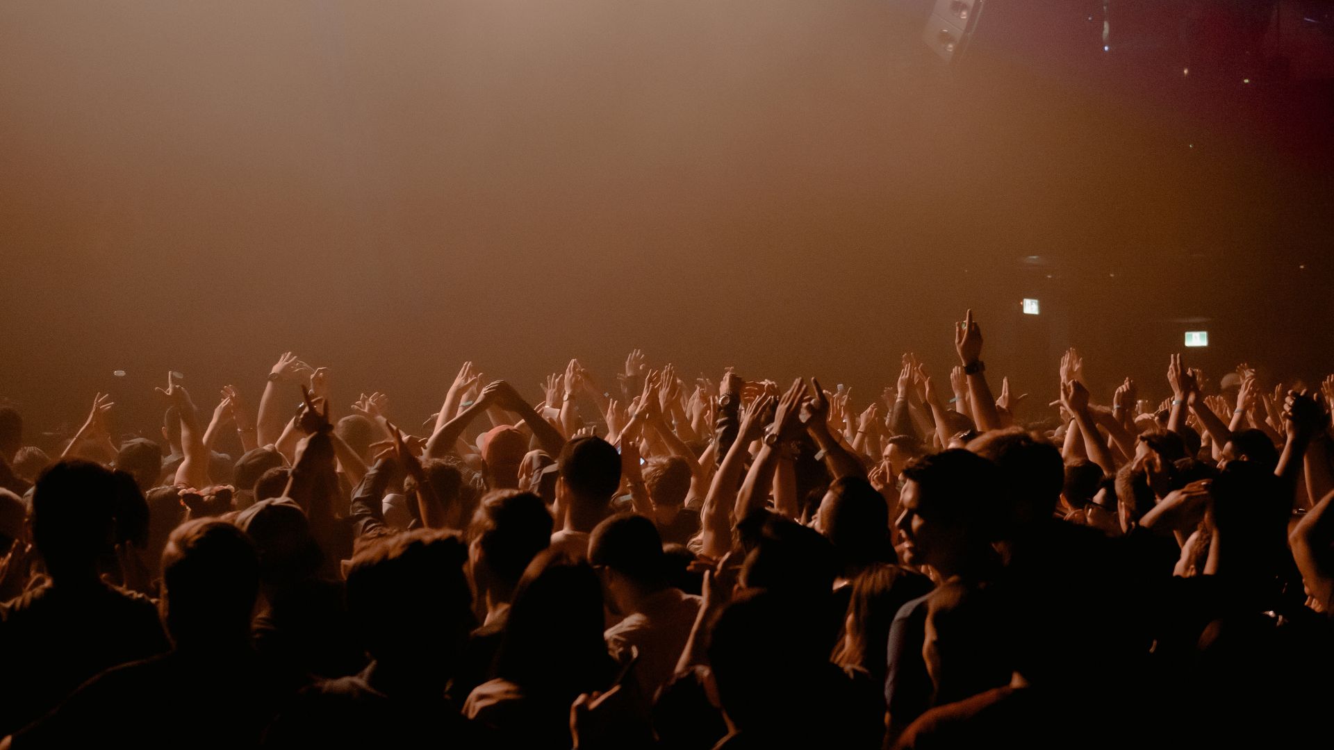 People worshipping in dark lighting with hands up