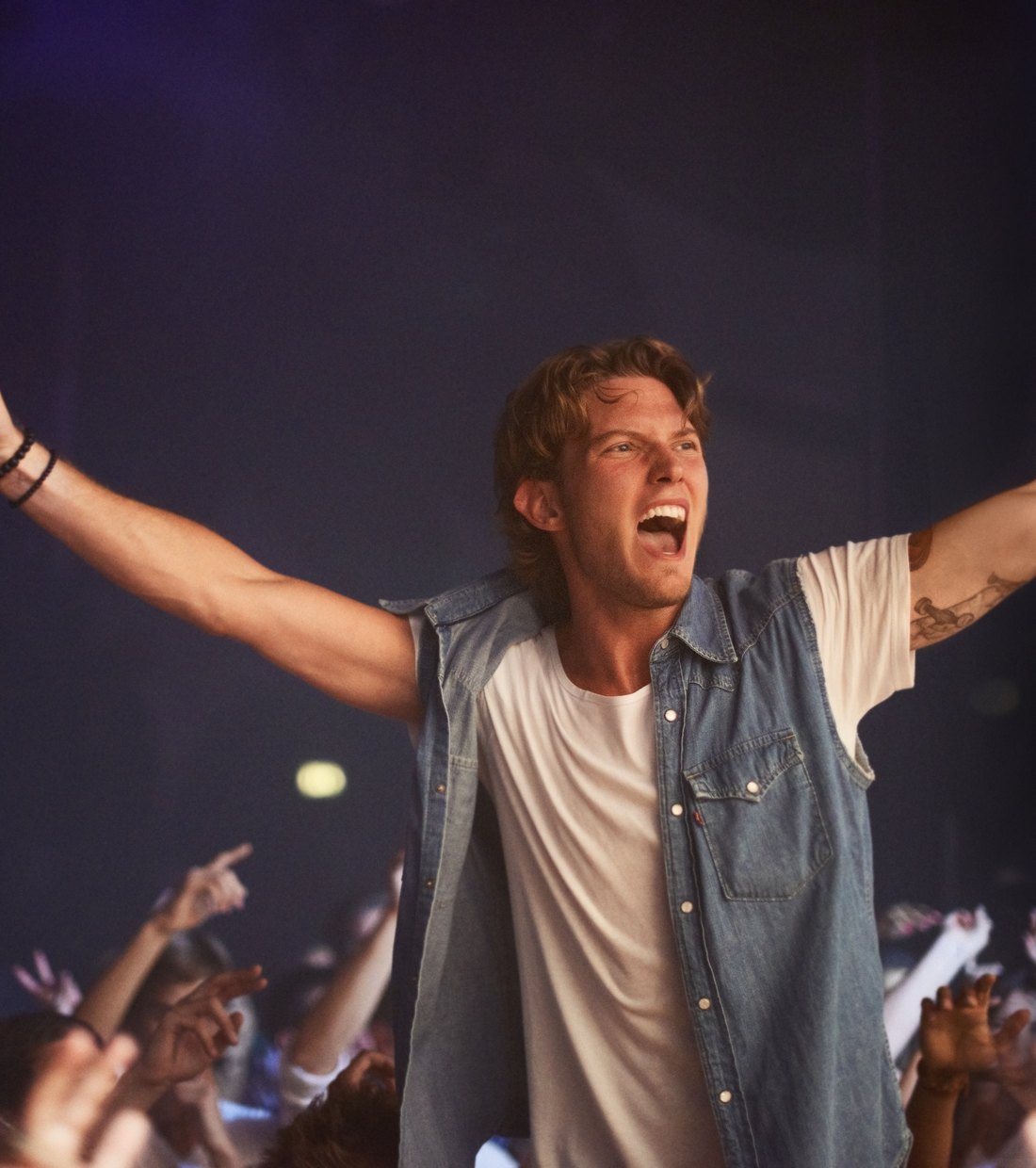 A performer with arms raised in front of an audience
