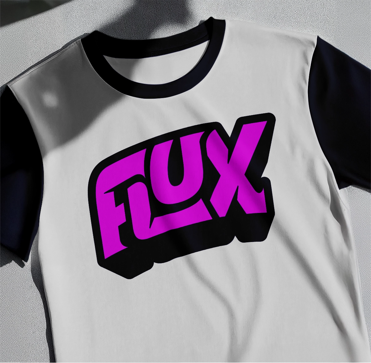 A white T-Shirt laying on a table with a pink Flux logo on it
