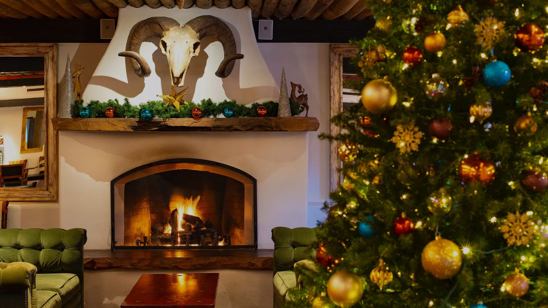 The Living Room with fireplace and green couches with a decorated Christmas tree