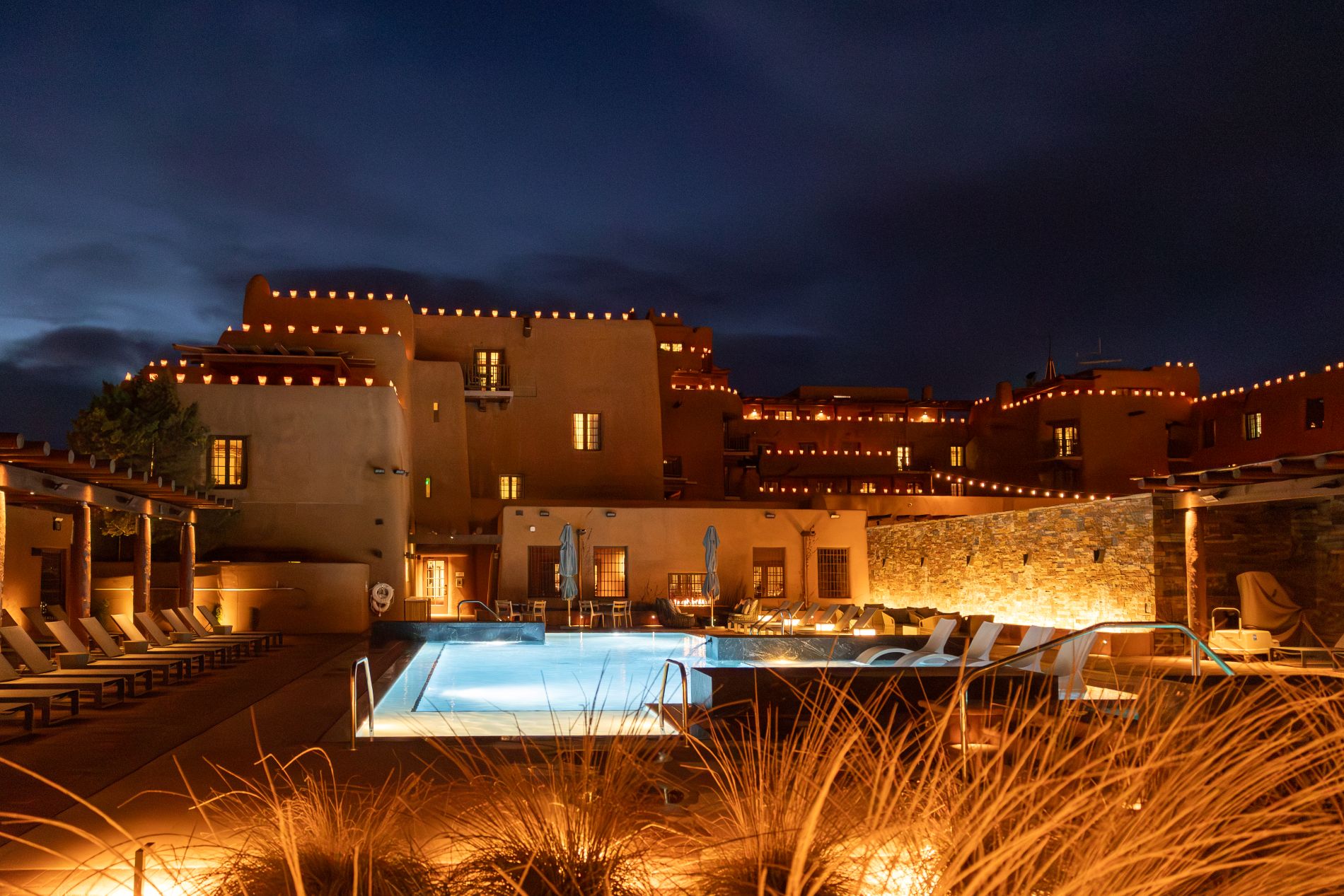 Pool with back view of Loretto at night with Luminarias lining the roof