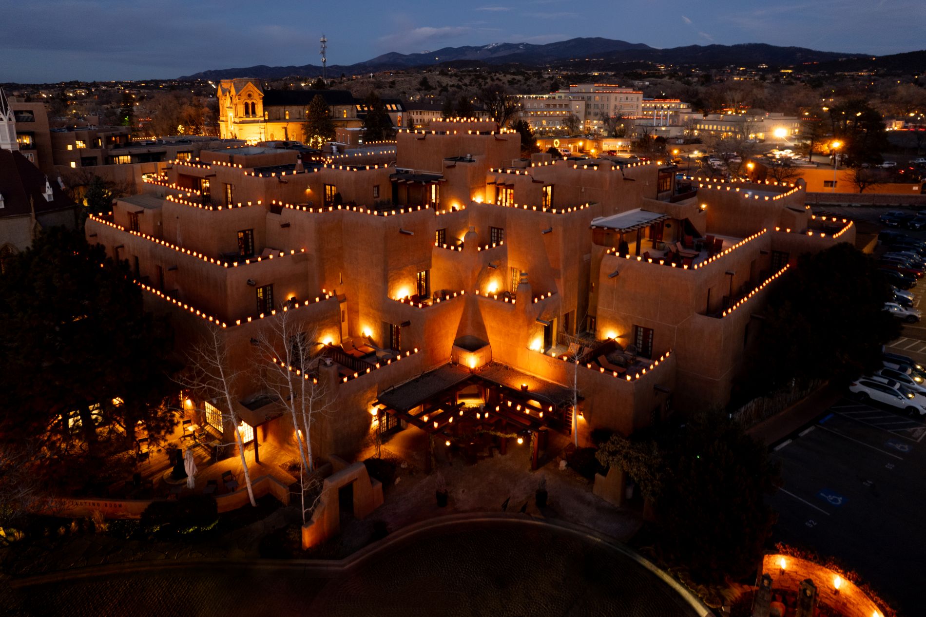 aerial image of Inn and Spa at Loretto at night with city in background and luminarias lining the roof