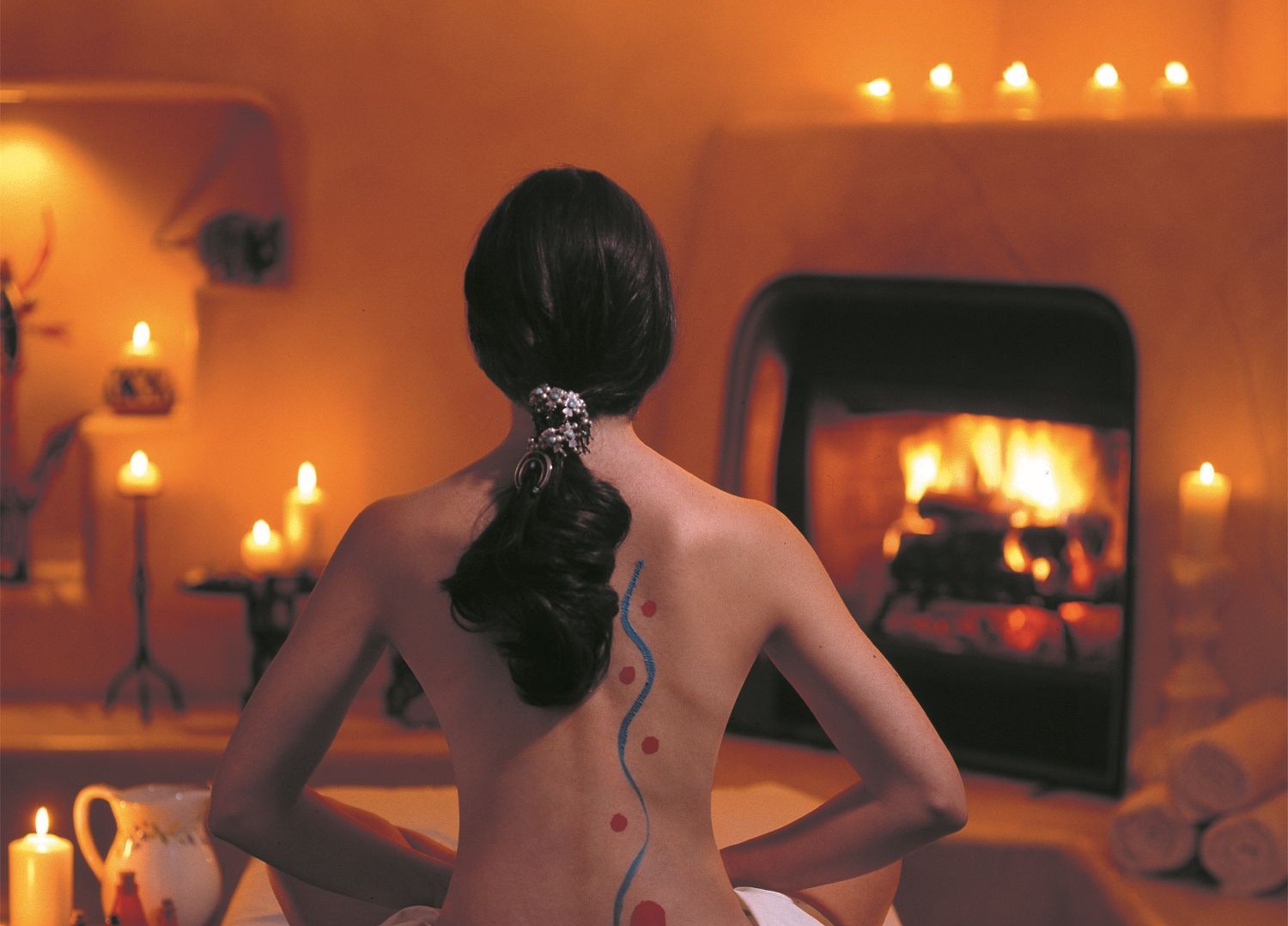 Woman with back facing camera facing fireplace