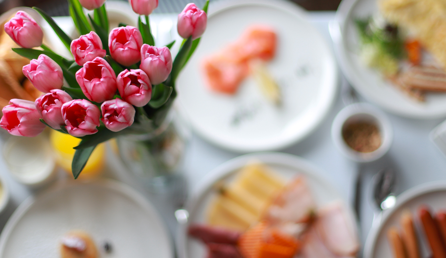 Table with dishes in background and vase with tulips