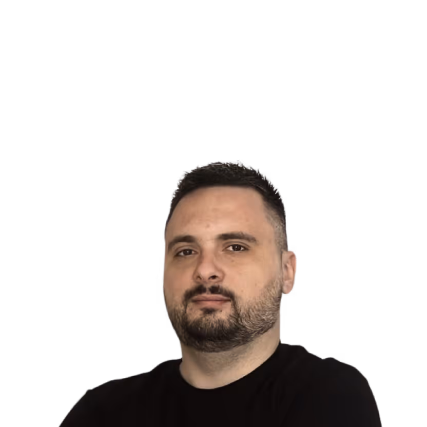 Man with short dark hair and a beard wearing a black shirt against a black background.