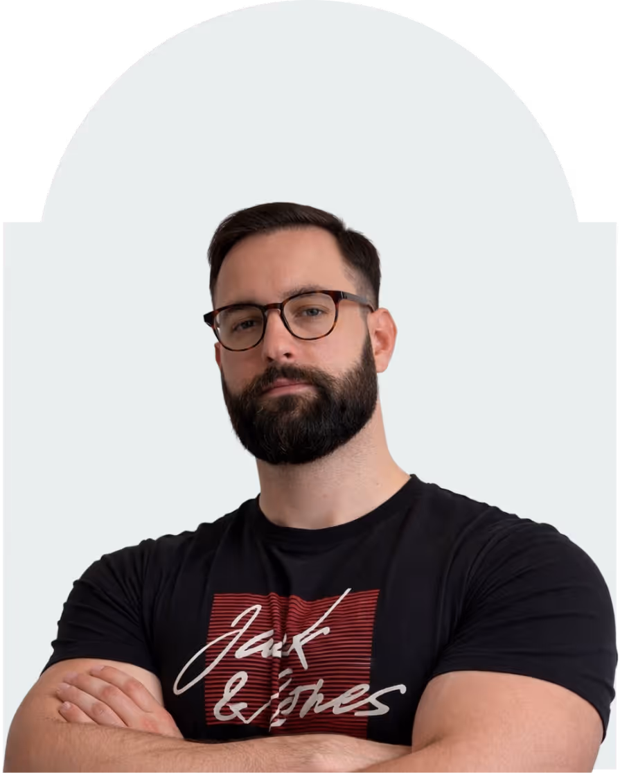 Bearded man wearing glasses and a black t-shirt with a red and white graphic, arms crossed.