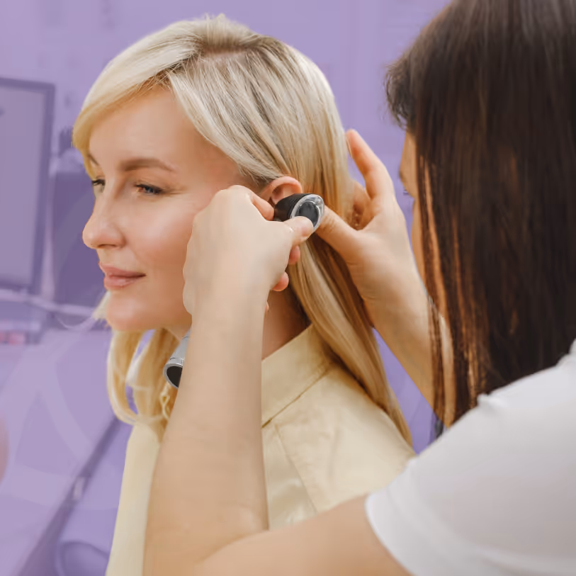 An ENT specialist examining a patient’s ear with an otoscope during a consultation.
