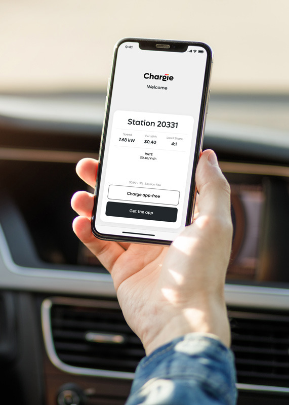 Driver in driver's seat holding up mobile phone with Chargie App screen