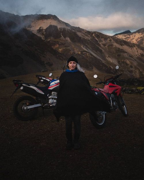 Marie-Christine Huot standing in front of dirtbikes in the Peruvian Andes