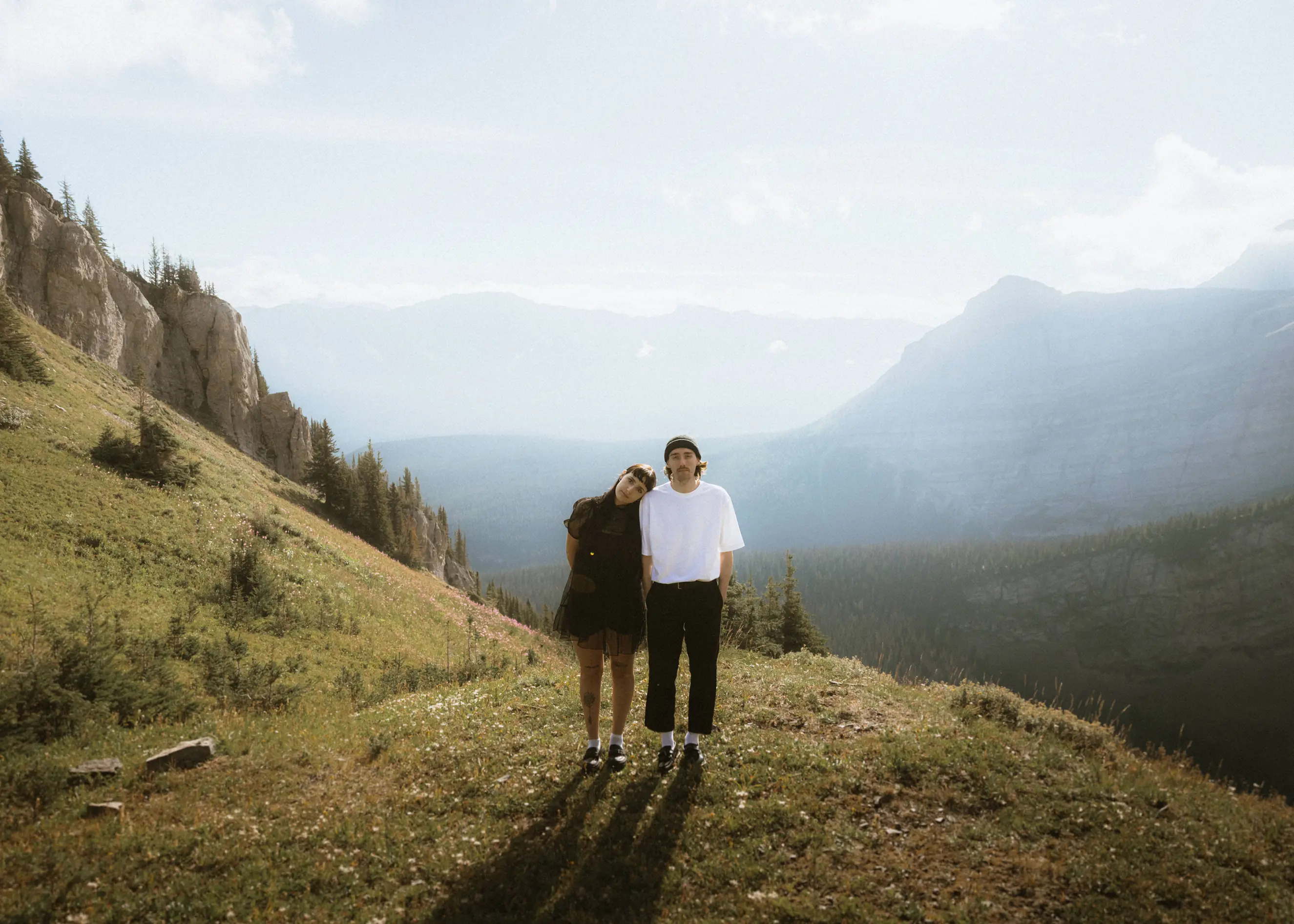 Alternative couple standing on a mountain ridge at sunrise