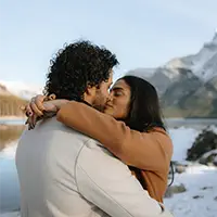 Romantic mountain kiss during Banff proposal photoshoot in Lake Minnewanka