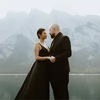 Elegant couple by glacial lake in formal attire during luxury elopement in Banff