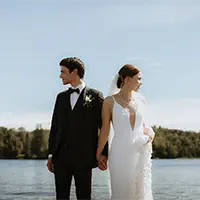 Bride and groom hold hands by alpine lake