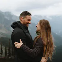 Couple embraces on mountain peak with valley views in British Columbia