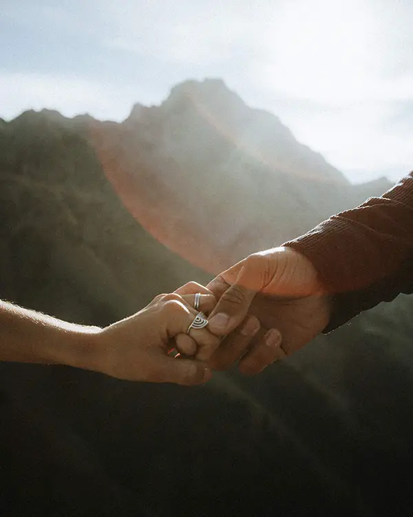 Hands holding with engagement ring against misty Banff mountain backdrop