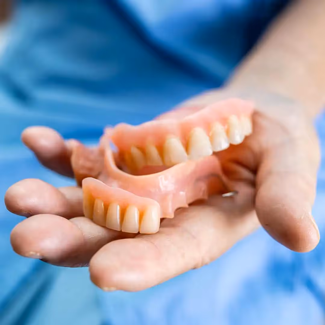A full and partial denture in someone's hand.