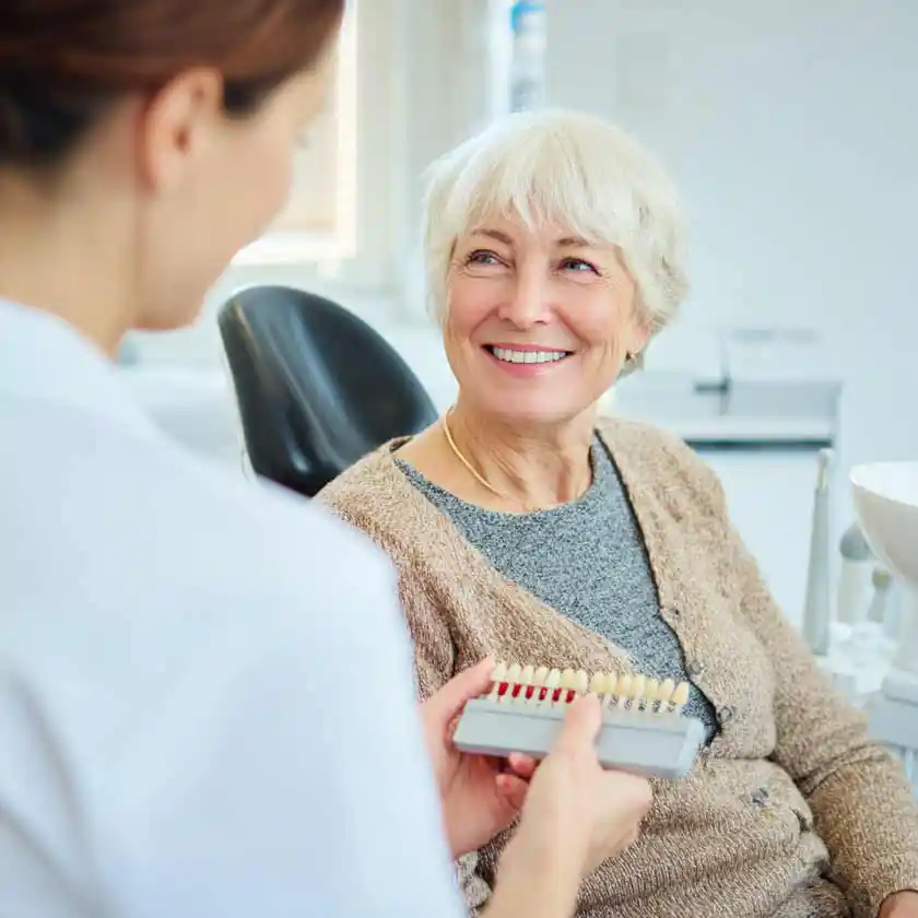 Elderly woman getting color matched for her dentures