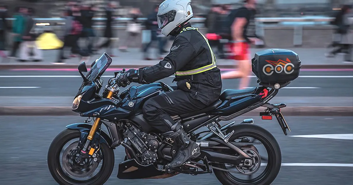 Man wearing a beanie and work clothes standing on a ladder in a hallway giving a thumbs-up.