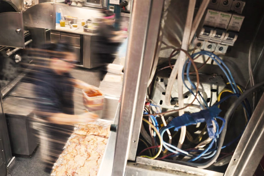 Man with headphones around his neck working on a wooden frame near black solar panels on a roof.
