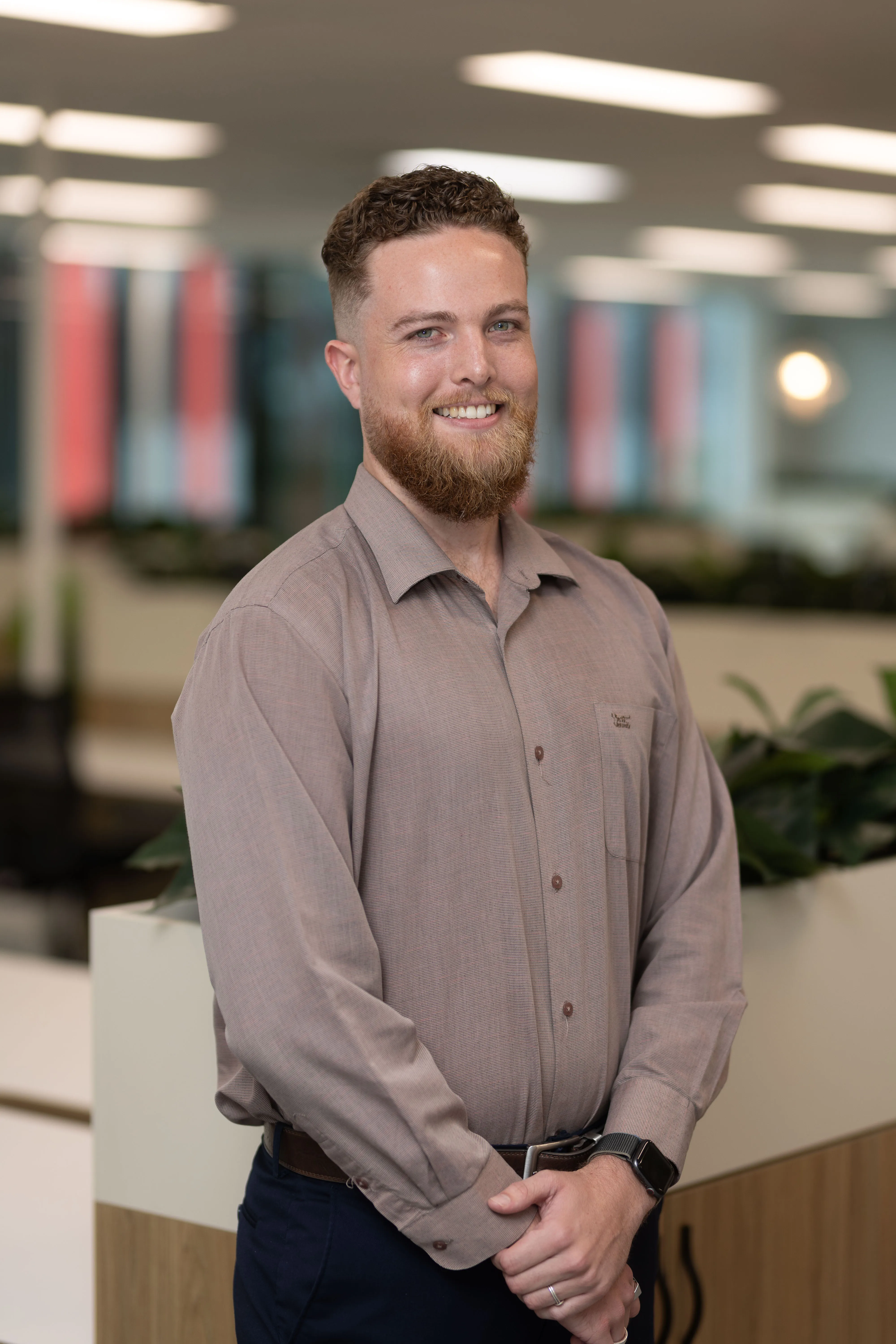 A man with a beard standing in an office.