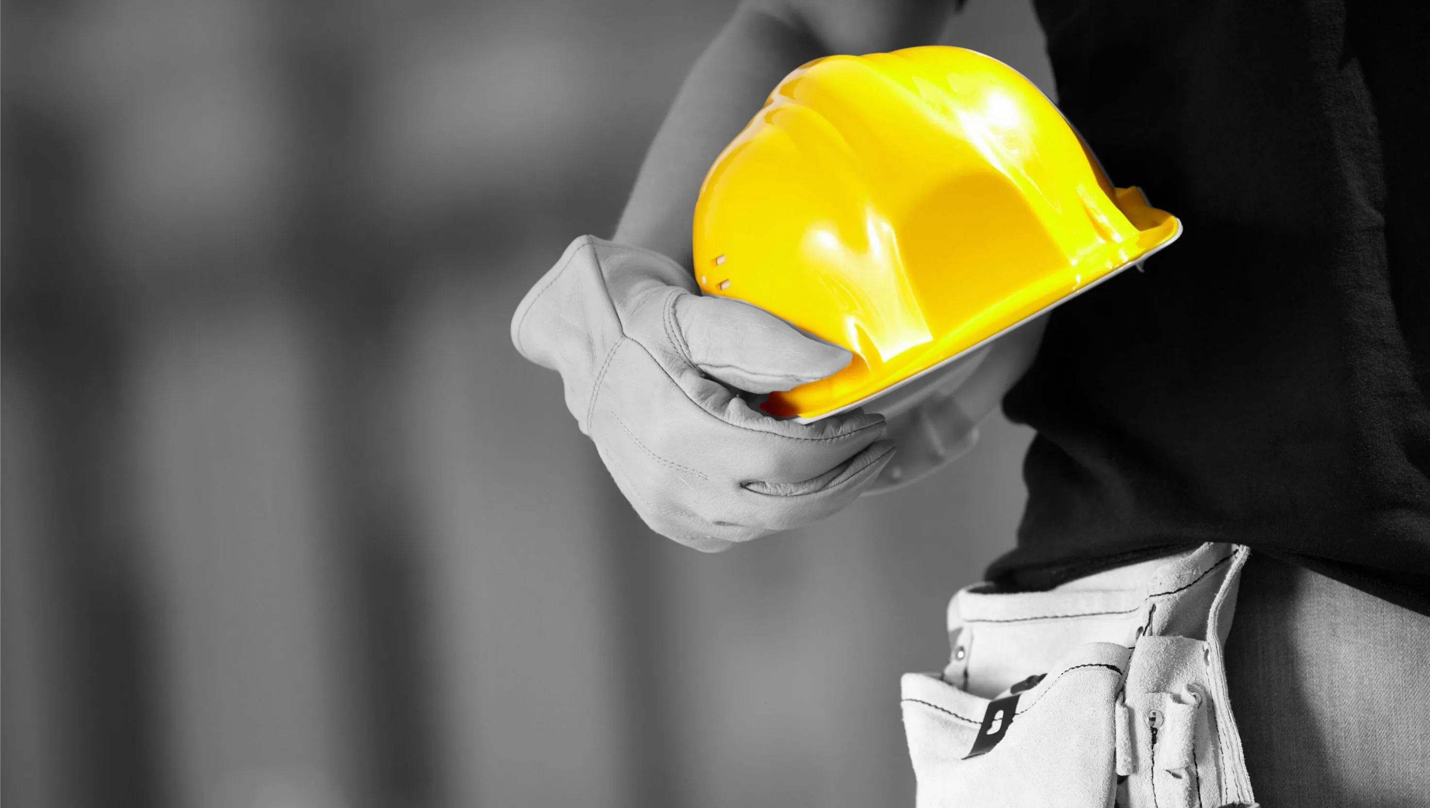 A construction worker holding a yellow hard hat.