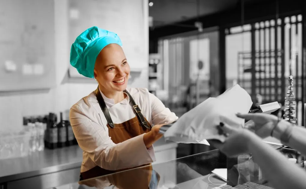 A woman wearing a blue head scarf and a chef's hat.